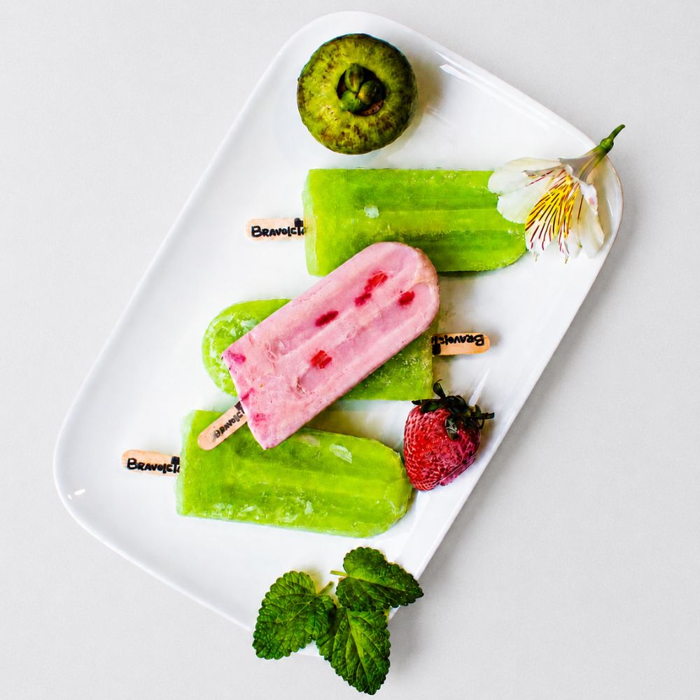 Paletas artesanales Bravoletas sobre plato blanco con frutas frescas.